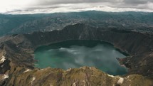 Drone shot of beautiful crater lake with green color surrounded by volcano in Ecuador - Birds eye view	