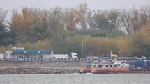 Flock Of Birds Flying Over Danube River With Transporter Ship In Background. - wide shot