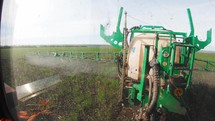 Tractor spraying green wheat field. Industrial machine fertilizing a field. Chemicals used by agricultural tractor.