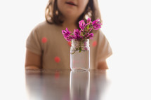 a girl child and flowers in a glass jar 