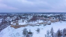 aerial view of an ancient fort surrounded by snow during winter in a small town 4K drone shot