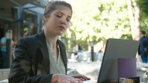 Young business woman sitting in a cafe working on a laptop computer and drinking coffee