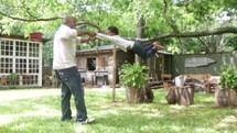 A father swings his young son around and around in the back yard.