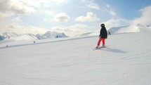 Winter holidays. Young female snowboarder rides down in the ski resort. Women snowboarder on snowboard running down the slope in Ski resort. Winter sport and recreation concept.