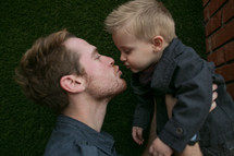 father kissing his toddler son