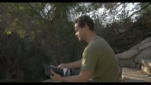 man reading a Bible and praying outdoors 