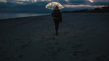 Girl enjoy the life on the beach with glowing umbrella
