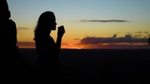 Silhouette of Happy traveler drinking coffee at sunrise while enjoying nature. 
