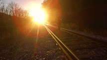 A man walking on train tracks under bright sunlight 