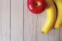 bananas and apple on a wood background 