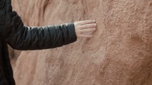 a woman in a coat touching a rock 