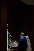 bride and groom praying before Mary statue 