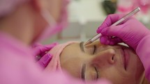 Make-up artist combing and styling eyebrows after the procedure of correction and coloring of eyebrows

