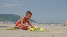 Kid playing sand with toy at the beach on summer vacation. Little child boy enjoy and have  fun outdoor activity playing.
