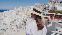 Tourist travel woman in Oia, Santorini, Greece. Happy young woman enjoying view. Beautiful girl visiting the Greek island.