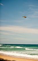 coast guard helicopter flying over a beach