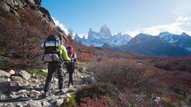 Young couple hiking, trekking in mountains with backpacks, enjoying their adventure - tourism concept at El Chantel Argentinean Patagonia

