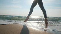 Legs of a young ballet dancer girl on sandy sea shore. 