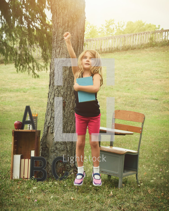 a little girl raising her hand ready for school 