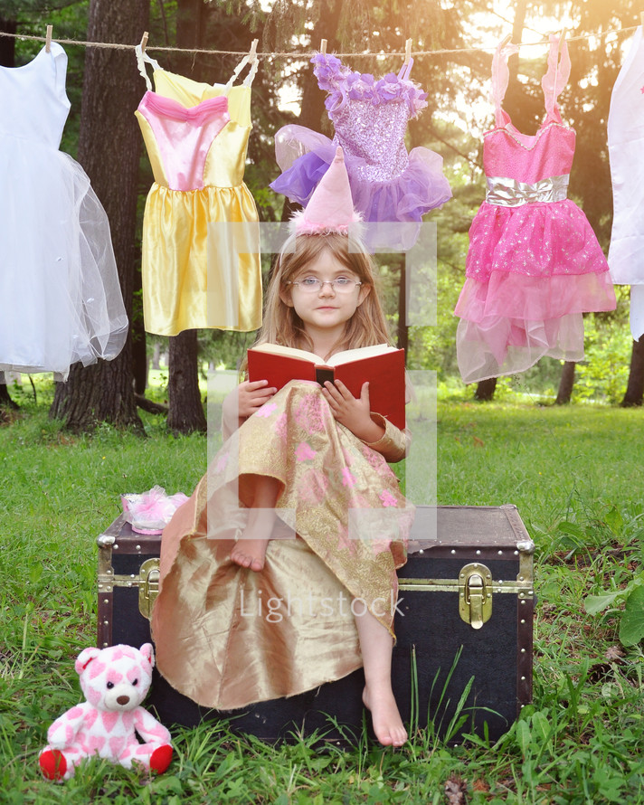 a child dressed up as a princess reading a book