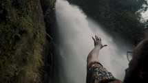 Close up of mans Hand In The Air Reaching Toward Devil's Cauldron Waterfall In Ecuador.