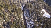 aerial view above a road through a winter forest 