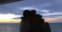 Son is hugging mother and father against sea sunset