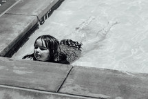 a little girl wadding in shallow water in a public pool 