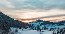 Beautiful Cloudy Sunrise With Golden Sun Rays Shining Behind Snowy Mountain Forest - Time Lapse in Fundata, Brasov, Romania