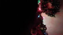 Girl Putting Ornament On Christmas Tree At Home. - Closeup, Pan Right