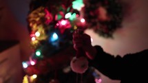 Side View Of A Girl Putting A Cute Frosty The Snowman Ornament On Christmas Tree. - Selective Focus