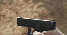 Slow motion of a hand gun firing in a firing range with cartridge flying away
