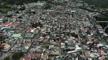 Baños de Agua Santa Town Nestled At The Base Of Tungurahua Volcano In Ecuador. Aerial Drone Shot	