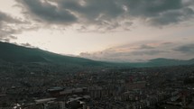 Aerial drone flight showing dusk vibes over Quito City and silhouette of mountain range in background	
