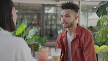 Over the shoulder shot of young man discussing business with female colleague over drinks in outdoor cafe
