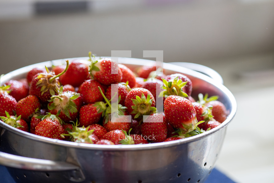 backlit colander full of strawberries