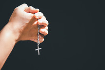 Hands clasped around a silver cross