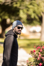 a man in a hoodie and sunglasses standing outdoors 