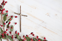 cross and red berries on white wood background