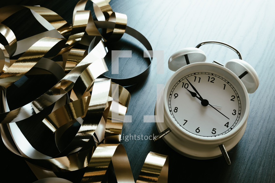gold streamers and alarm clock on a dark background