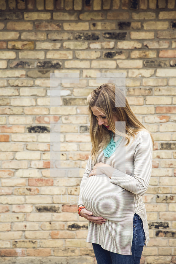 a pregnant woman holding her belly and smiling 