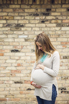 a pregnant woman holding her belly and smiling 