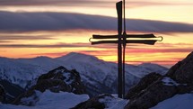 Catholic cross on top of a mountain in winter at Christmas.Iron wrought iron cross commemorating the crucifixion of Jesus.In the background pastel colored clouds at the end of the day