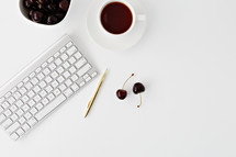 computer keyboard, gold pen, cherries, coffee cup 