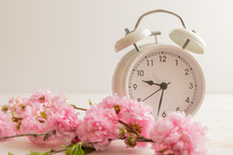 White alarm clock with pink flowers on a white background