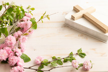 Bible, wood cross and spring blossoms on a white table with copy space