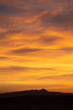 Vivid yellow sunrise over silhouette mountain peak range vertical