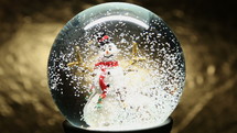 snow falling on a snowman in a snow globe