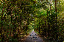 A bicycle in the middle of a road in a forest.
