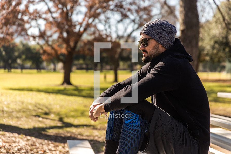 A man in workout clothes sitting in a park.